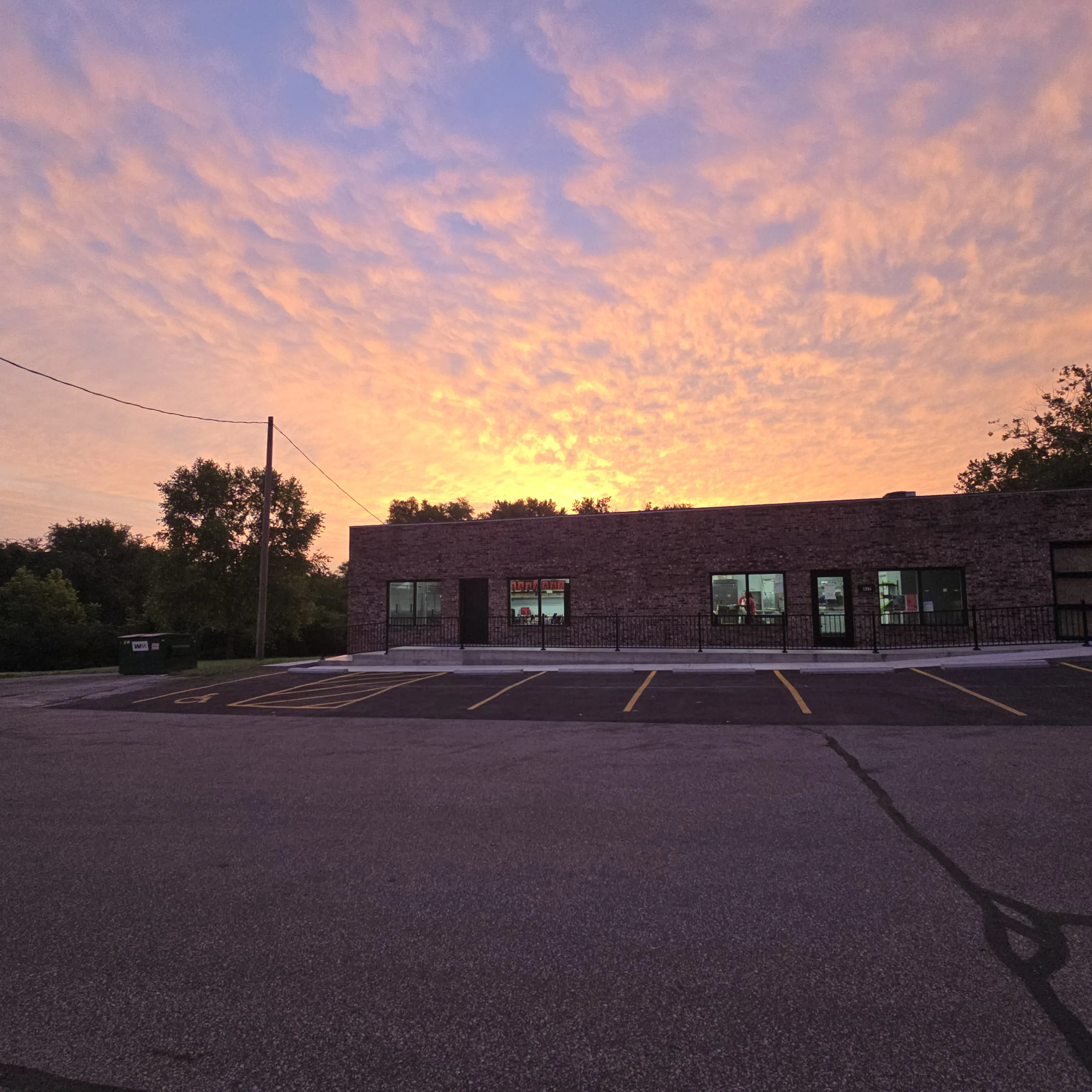 The Cafe storefront at sunrise, lights on inside the windows