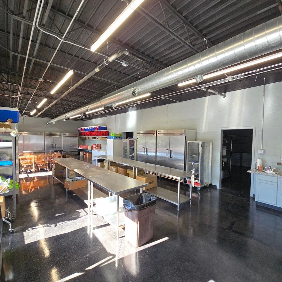 Commercial kitchen prep area with stainless steel tables and refrigerators