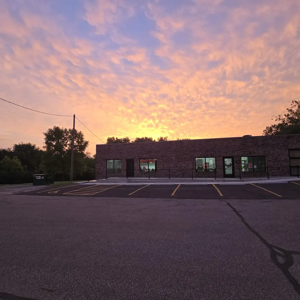 The Café's storefront at sunrise under orange and purple clouds.